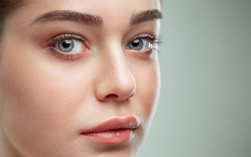 The beautiful female face. The perfect and clean skin of face on gray